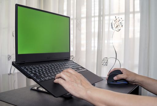 A closeup of a person working on a  laptop with green screen space