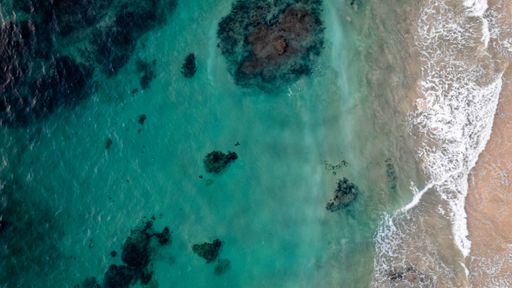 An aerial view of the turquoise waters of the oceans near the beach