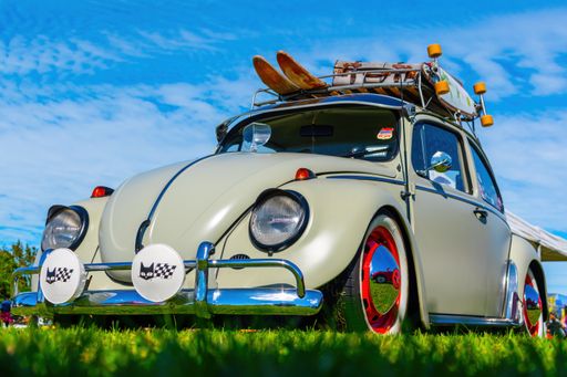View of old classic Volkswagen Beetle on green grass with blue sky in background