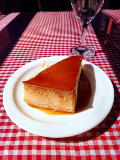 High angle shot of a piece of healthy delicious sweet creamy homemade flan on a white plate. Classic dessert made of eggs, milk and sugar