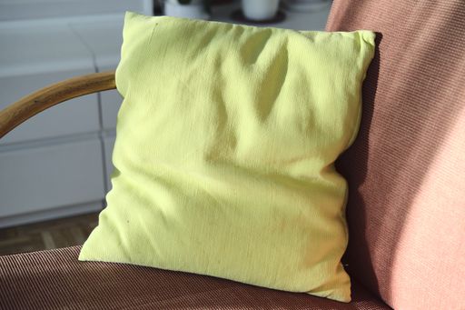 A closeup shot of a yellow cushion on the armchair