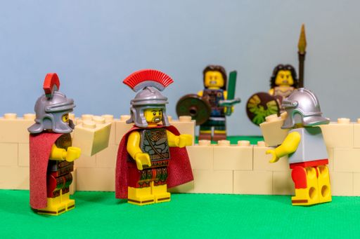The miniature Lego toy soldiers in armor building a wall with blocks