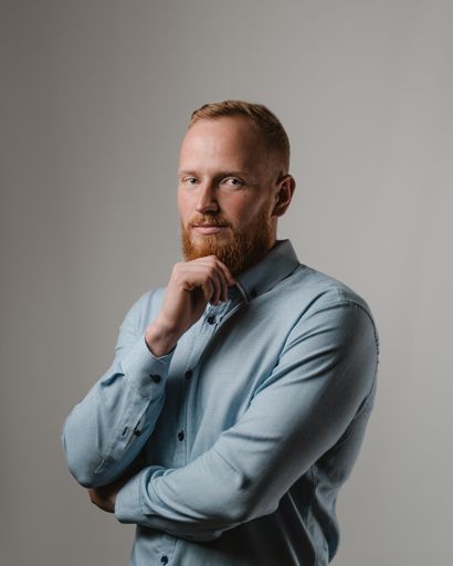 A vertical shot of a handsome Caucasian redhead man from Lithuania posing on a gray background