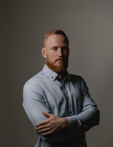 A vertical shot of a handsome Caucasian redhead man from Lithuania posing on a gray background