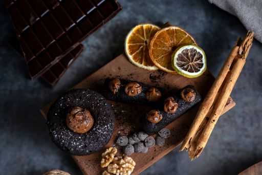 A cakes puddings, chocolate muffins with blueberries, cream cherries, and dried citrus on a wooden plate.