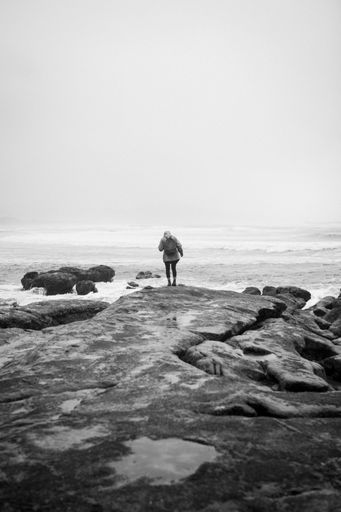 A verticcal shot of the ocean from the Pacific Coast Highway with a woman looking off into  distance.