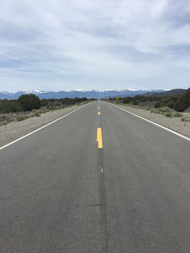A scenic view of a two-lane highway winding through a mountainous landscape