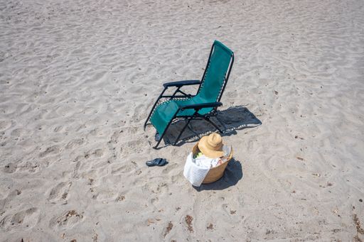 secluded lounger on the beach, sandals and a basket with beach items and a hat