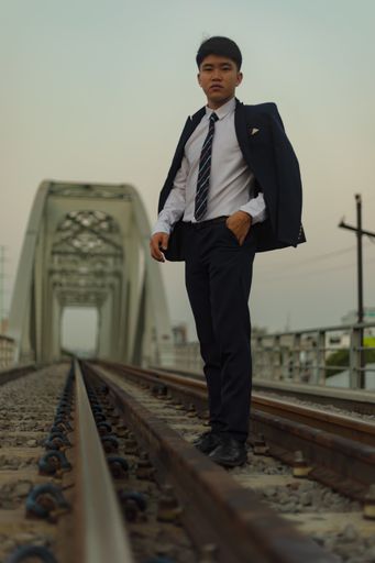 A young Asian businessman standing in the middle of a railway with coat over his shoulder