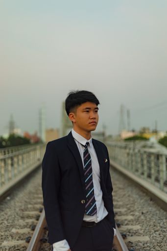 A young Asian businessman standing in the middle of a railway looking away
