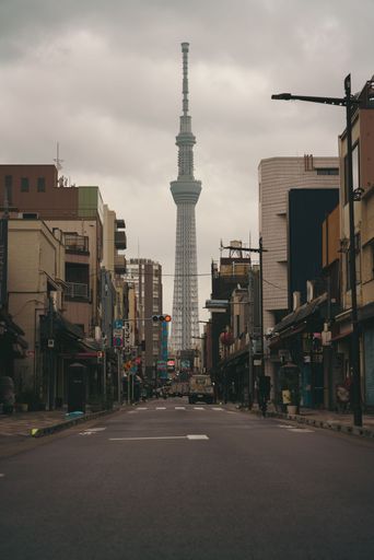 This image depicts a deserted city street with a multitude of tall buildings and a single, impressive tower in the background