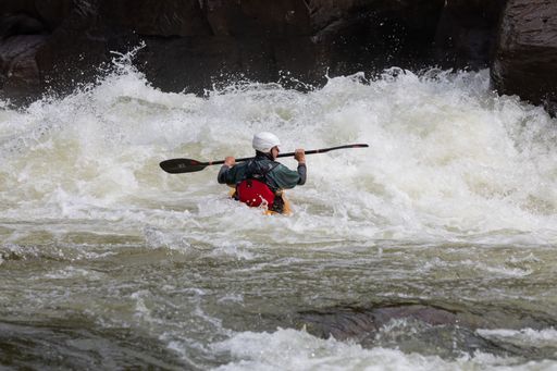 A person in a kayak navigating through the choppy waters of a river in Somerville, USA.