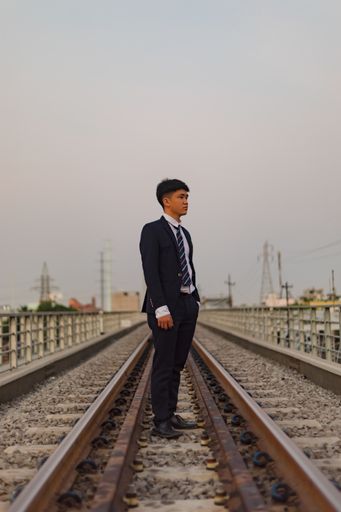 A young Asian businessman standing in the middle of a railway looking away
