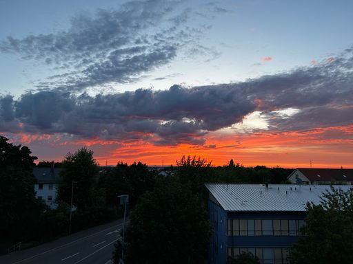 A scenic view of a beautiful sunset in the clouds above residential houses