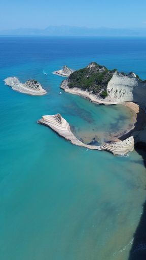 An aerial view of the rocky shoreline of Corfu, Greece with its crystal clear blue ocean waters.