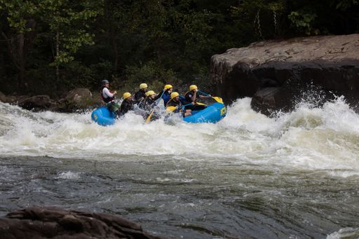 A group of people in a kayak navigating through the choppy waters of a river in Somerville, USA.