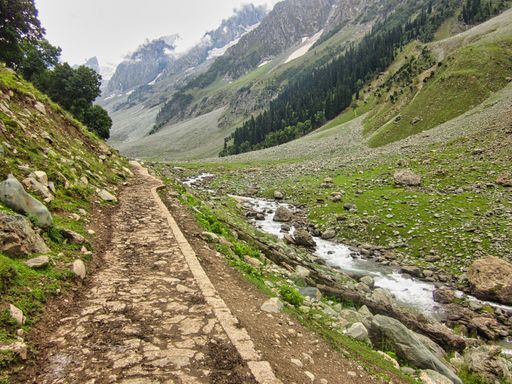 A long pathway surrounded by rocky hills and fields of grass in the mountains