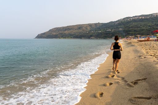 A beautiful young latina female in athleisure running on a sunny beach