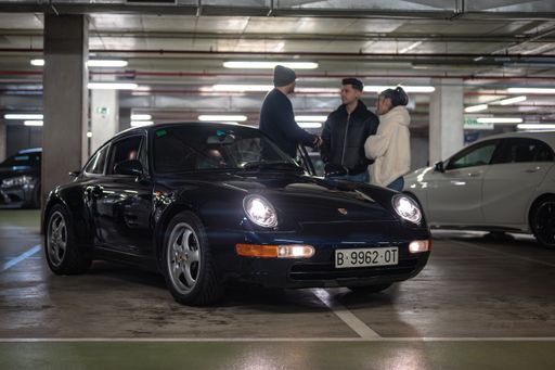Front view of a classic German sports car, the black colored Porsche 993 parked in the garage with some boys