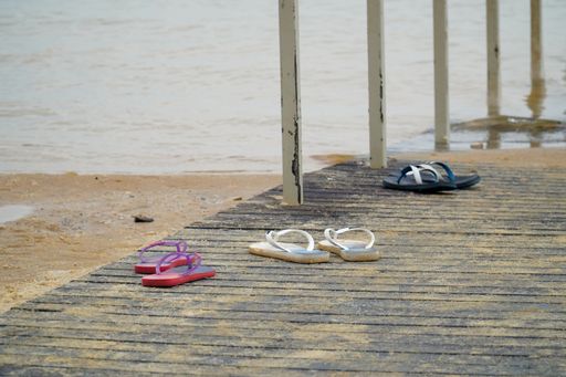 A closeup shot of flip flops on a wooden pier at the beach of the Dead Sea in Israel