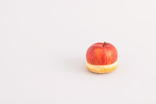 A closeup shot of a half of an apple on top of the donut - creative healthy food concept