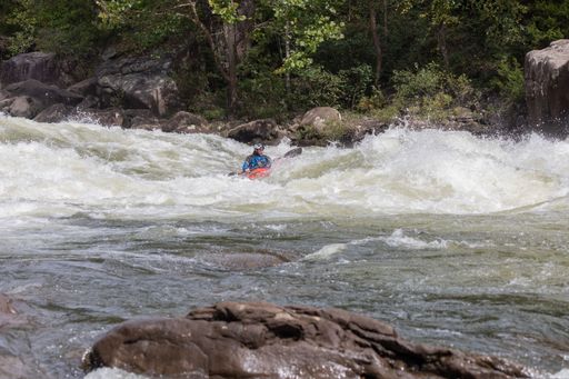 A person in a kayak navigating through the choppy waters of a river in Somerville, USA.