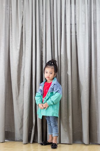 A vertical shot of a cute Southeast Asian baby girl posing for the camera