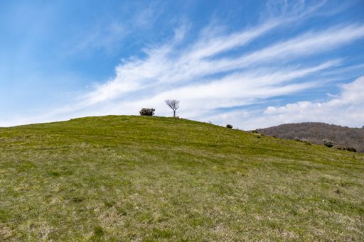 A low angle shot of a gorgeous green hill under a bright blue sky littered with clouds