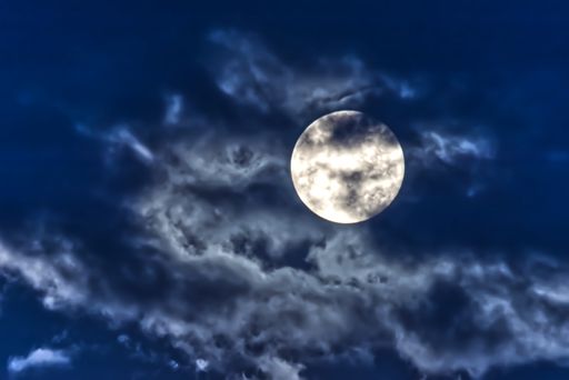 A closeup shot of the full moon on the cloudy sky background