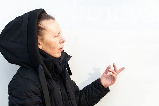 A portrait of a Caucasian middle-aged woman in a black coat, looking aside on a white background