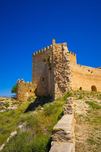 A vertical shot of the ruins of an old castle built on top of a hill with clear blue sky above