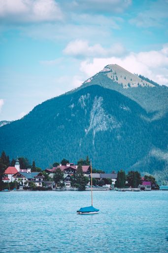 The sea with boats on it surrounded by hills covered in forests under the sunlight