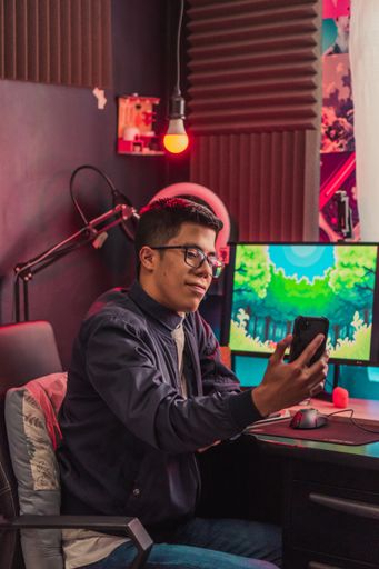 A vertical shot of a young gamer male going live from his phone