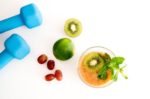 A top view of kiwi fruit juice with mint, grapes, citrus, and dumbbells isolated on white background