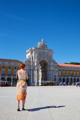 Vertical shot of a beatiful woman stood infront of the Arco da Rua Augusta in Lisbon portugal