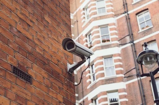 A camera on an apartment building under the sunlight with a blurry background