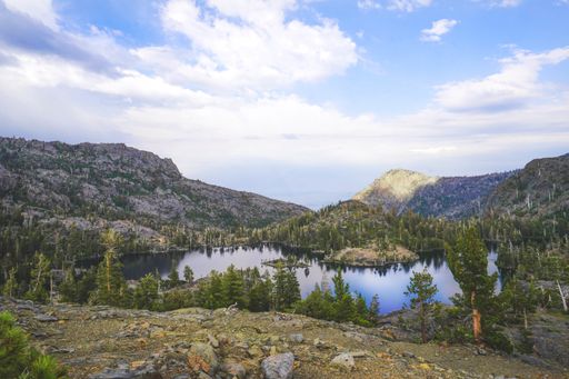 A mountains with trees surrounding it  near Lake Tahoe, CA with cloudy sky in the background