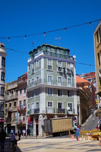 Quiet streets in Lisbon Portugal with a beautiful green colourful building standing out on the corner of a street.
