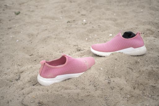 A closeup shot of pink shoes on the sand