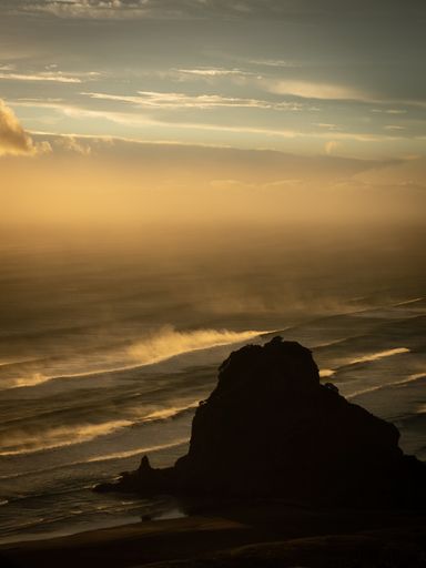 View of Piha Lion Rock during stormy weather in sunset light