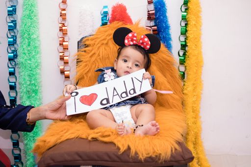 A closeup shot of a cute happy Indian female baby sitting on a teddy bear holding an i love daddy sign