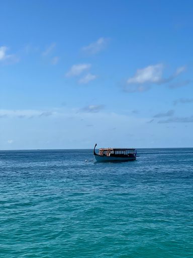 A vertical shot of a boat on bright blue water under a clear sky