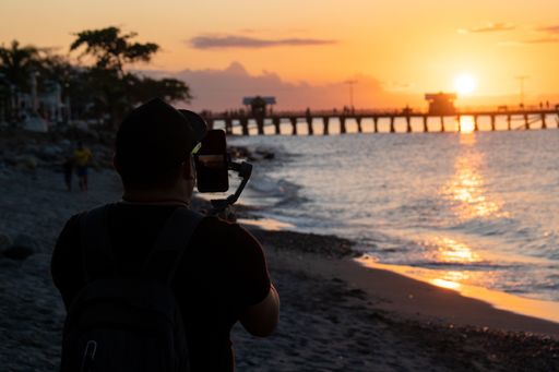 A man taking a picture of a beautiful sunset on the beach