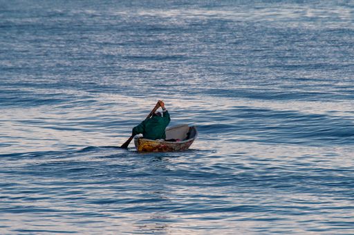 A man rowing his small boat in an open sea