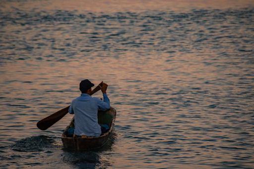 A man rowing his small boat in an open sea
