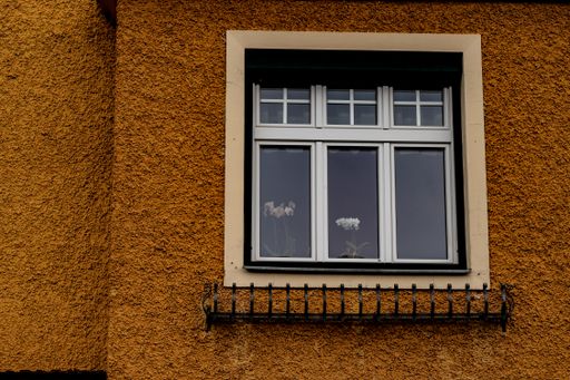 A window with wrought iron rails for flowers and flowers on the windowsill