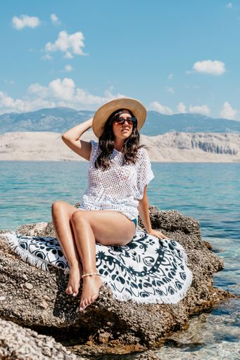 A vertical shot of a beautiful sexy woman with a hat and sunglasses enjoying summer sea