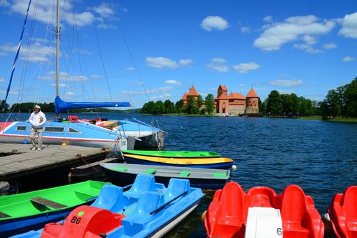 In the foreground, brightly colored small boats on Lake Galve, near Vilnius, in Lithuania. In the background Trakai Castle and its island.
