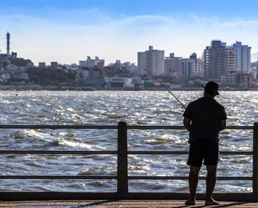 A closeup shot of a fisherman standing on a bridge and catching fish