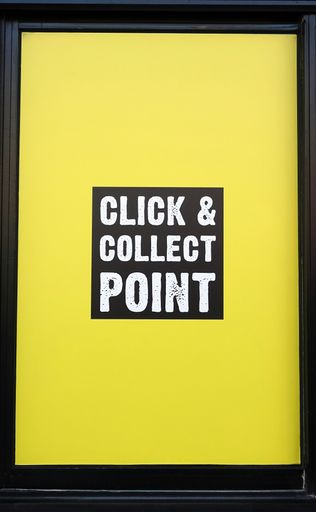 A yellow screen framed by wood saying "click and collect point" - shopping sign about trade